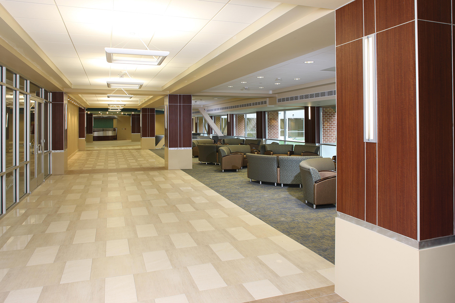 Visage sconces in a sleek hospital lighting design, illuminating a waiting area adjacent to a wide corridor and reception desk.