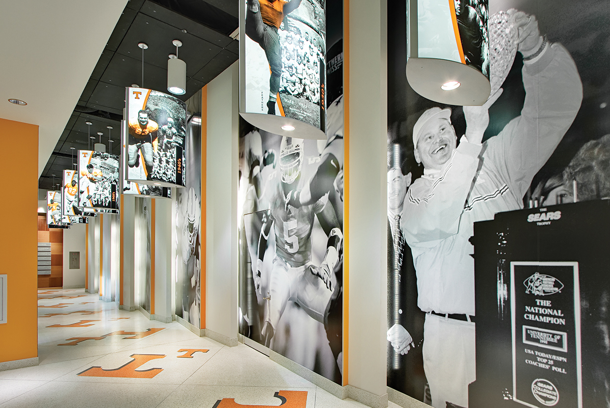 Air Foil custom light fixtures with photograph panels depicting college football players along a stadium hallway. 