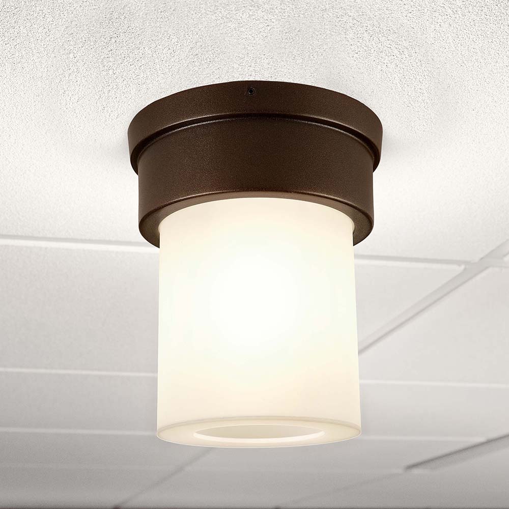 A small, luminous ceiling-mounted cylinder fixture with a solid base