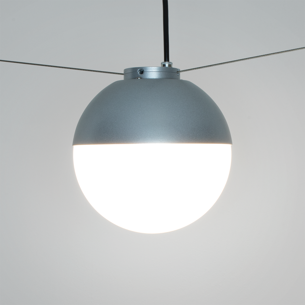 Small globe pendant for outdoor patios with tether catenary cable. 