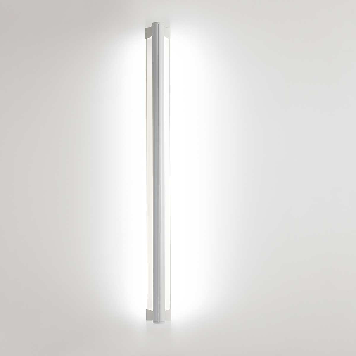 A surface mounted linear luminaire with a body that curves into the base with hidden indirect lighting