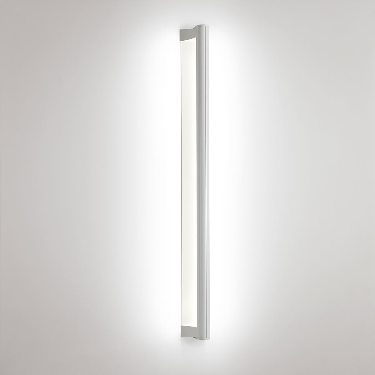 A surface mounted linear luminaire with a body that curves into the base with hidden indirect lighting