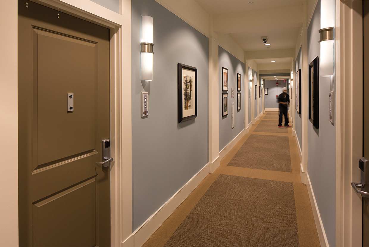 Pila sconces are ideal for hotel or apartment lighting applications, seen here alongside doors in a hotel hallway.