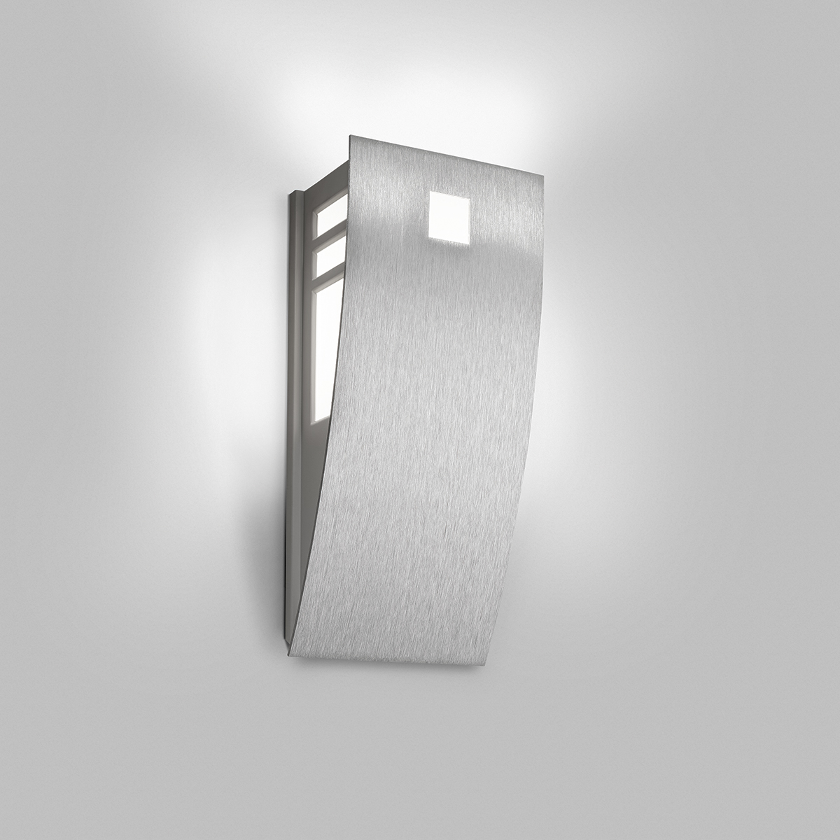 A wedge-shaped curved wall sconce with cutout accents in its solid body and uplighting