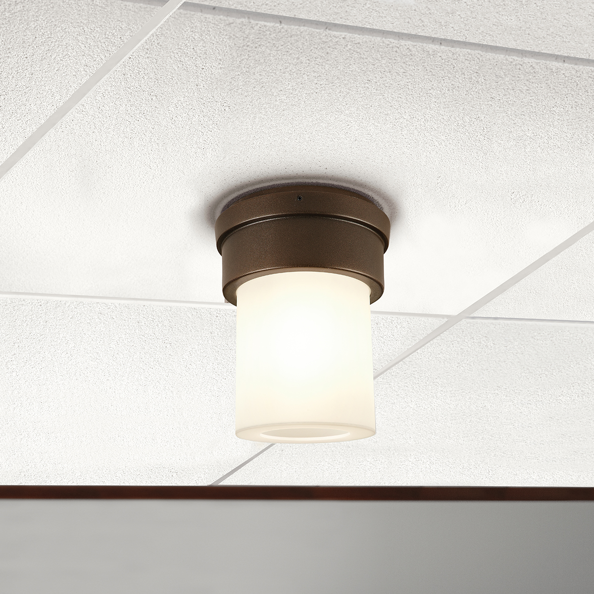 A small, luminous ceiling-mounted cylinder fixture with a solid base