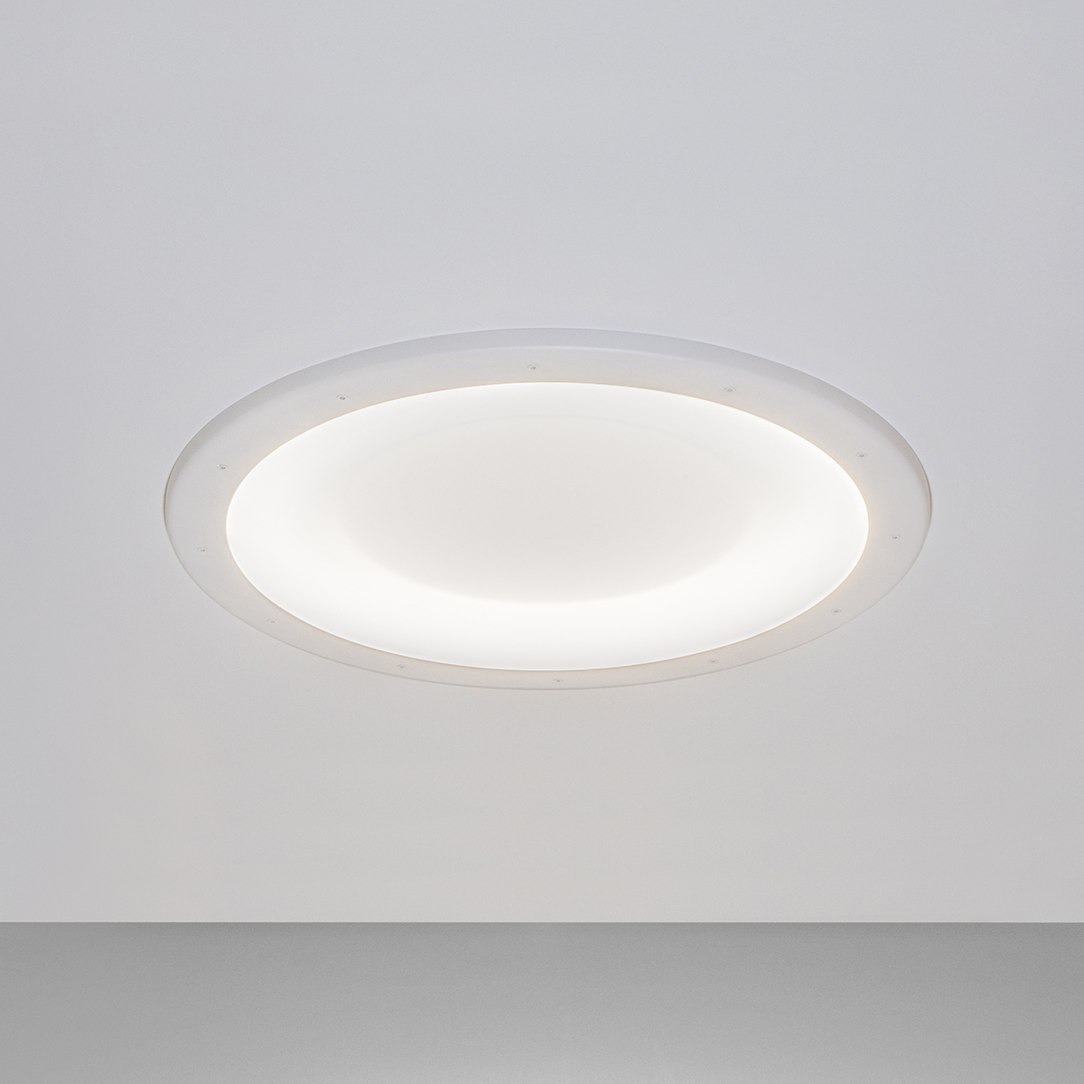 A round, recessed ceiling luminaire with a concave dome lens 