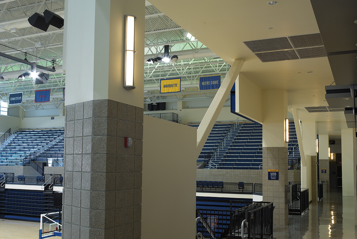 Avatar wall sconces with minimal accent provide modern lighting design for a college basketball gym. 