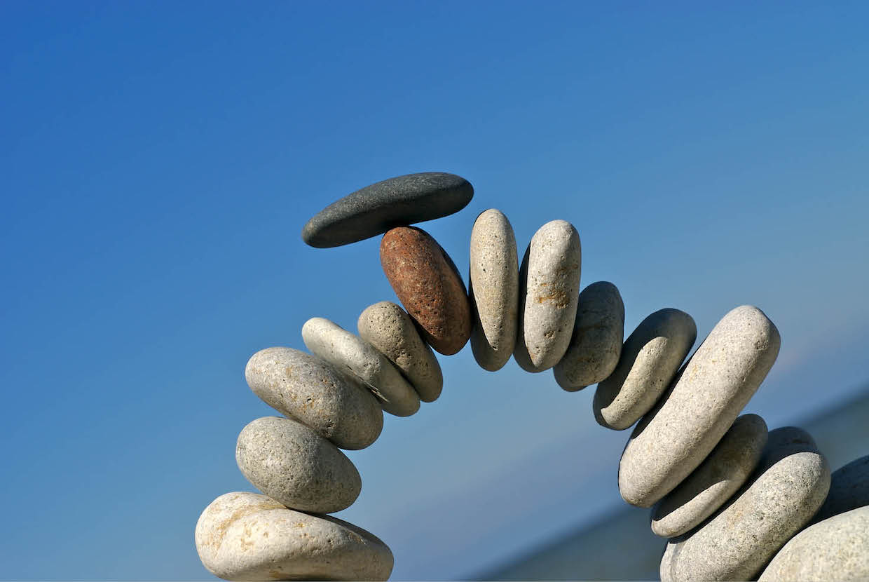 Rocks at a beach balanced in an arch shape illustrating the delicate nature of behavioral health design