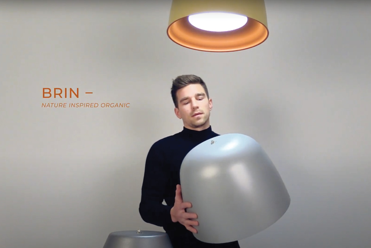 Product designer holds up the Brin pendant light housing