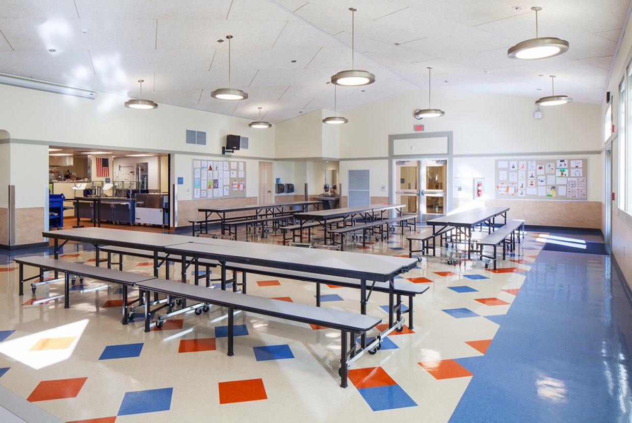 Broadway pendant luminaires as classroom or cafeteria lighting, hung over tables in a school cafeteria. 