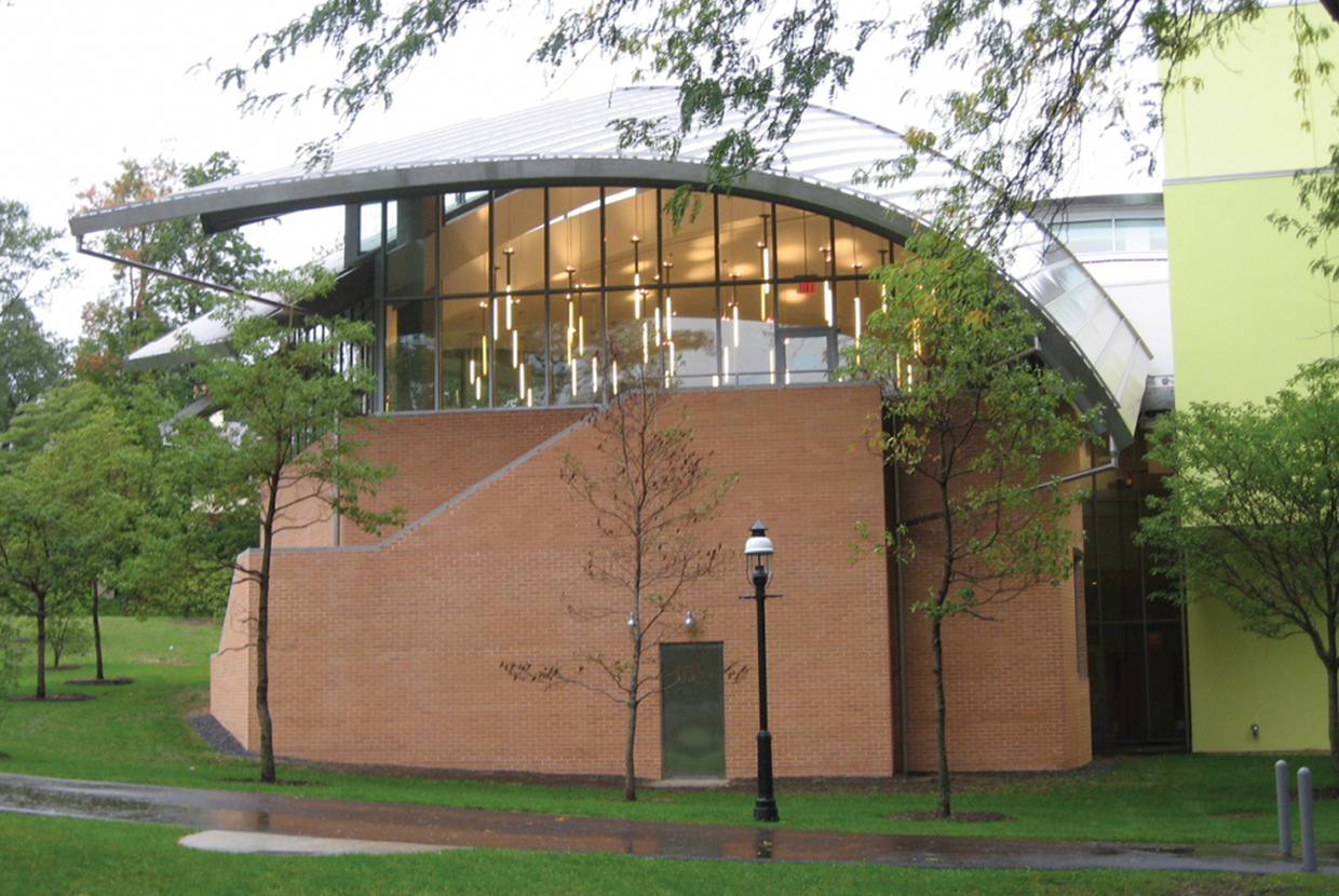 Several luminous tube custom light fixtures in a brick university building, viewed from the outside into large windows.