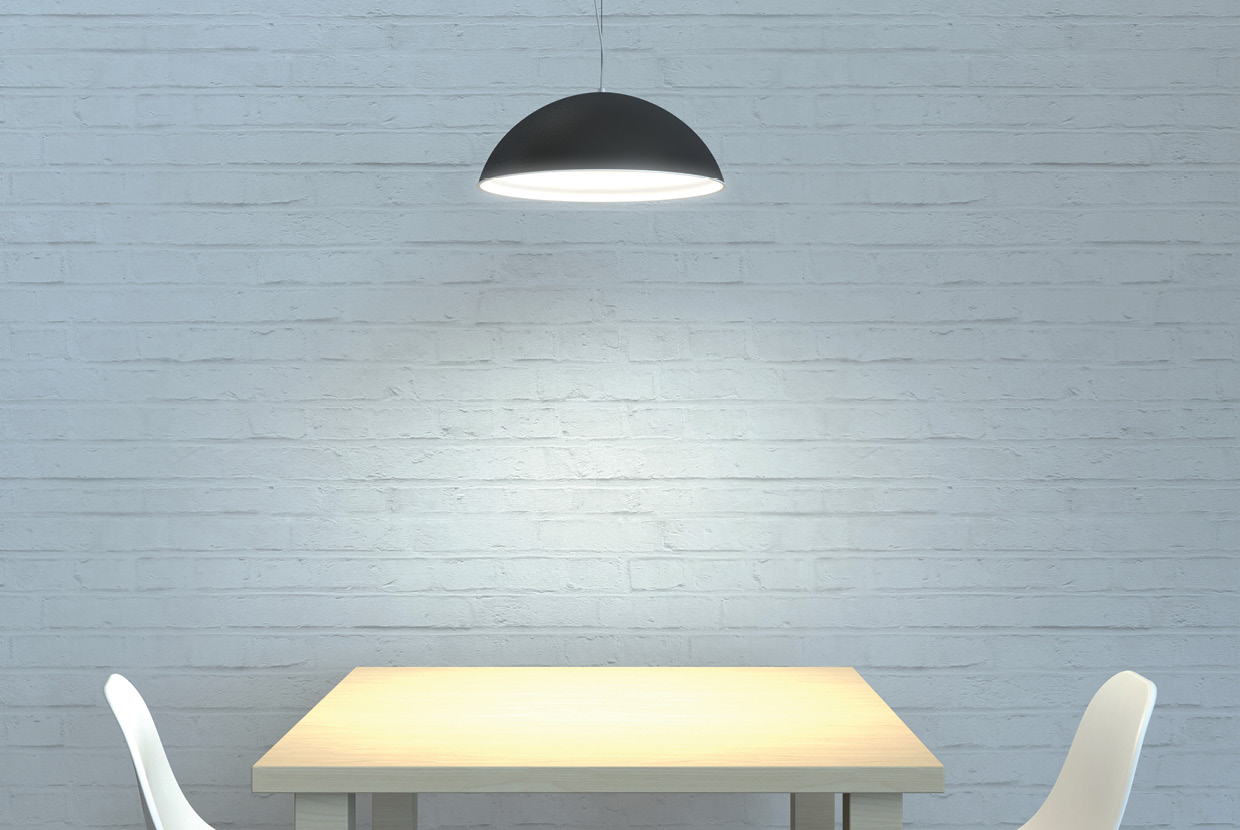 Black and white dome pendant light hung over work table. 