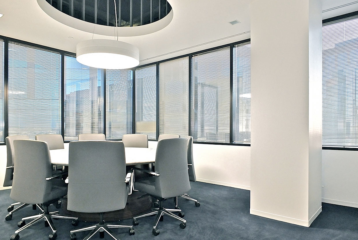 Omnience office lighting fixtures are perfect for conference tables, seen here above a small round table near large windows. 