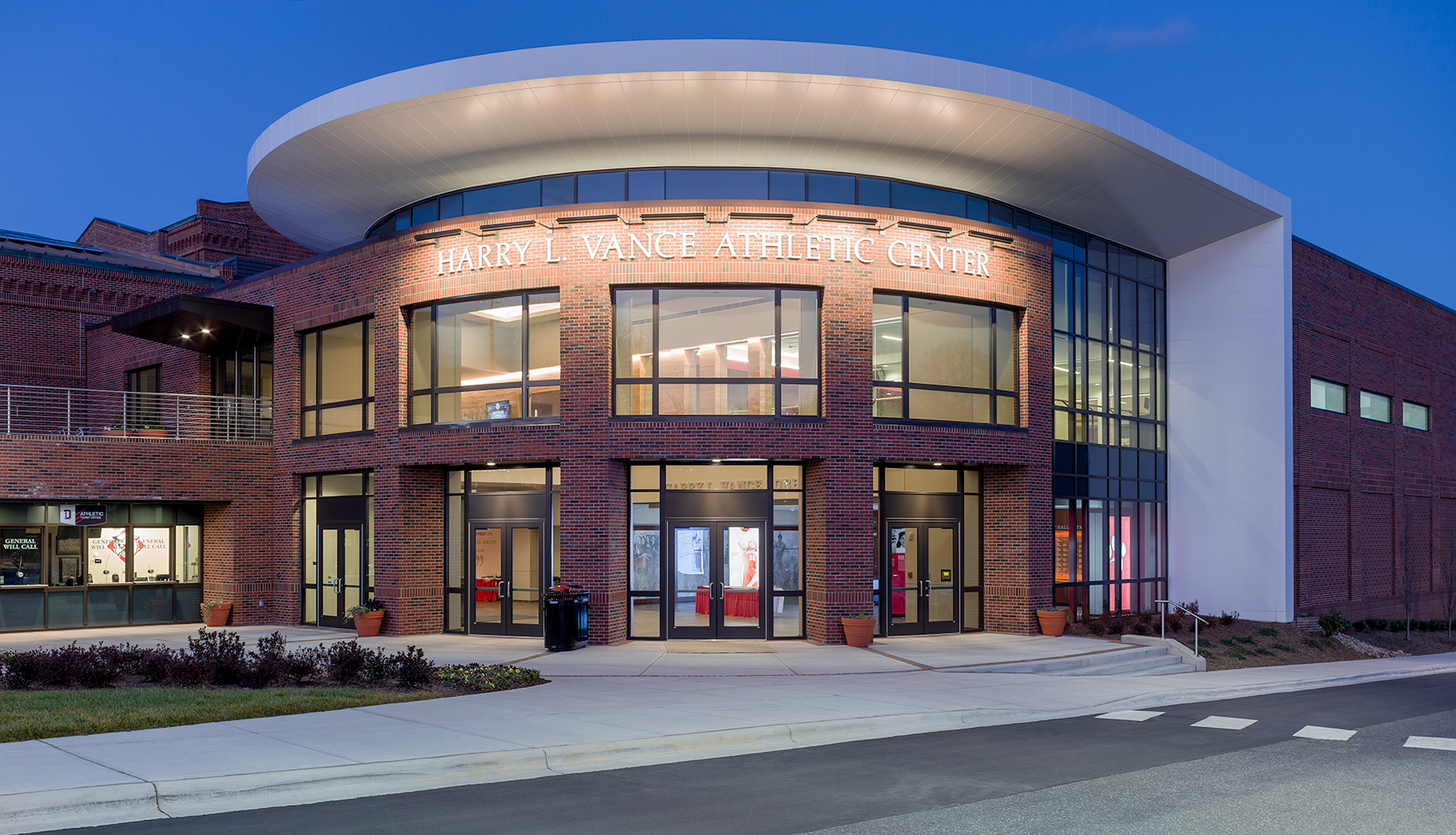 Advantus exterior lighting fixtures illuminate a sign on an athletic center at night.