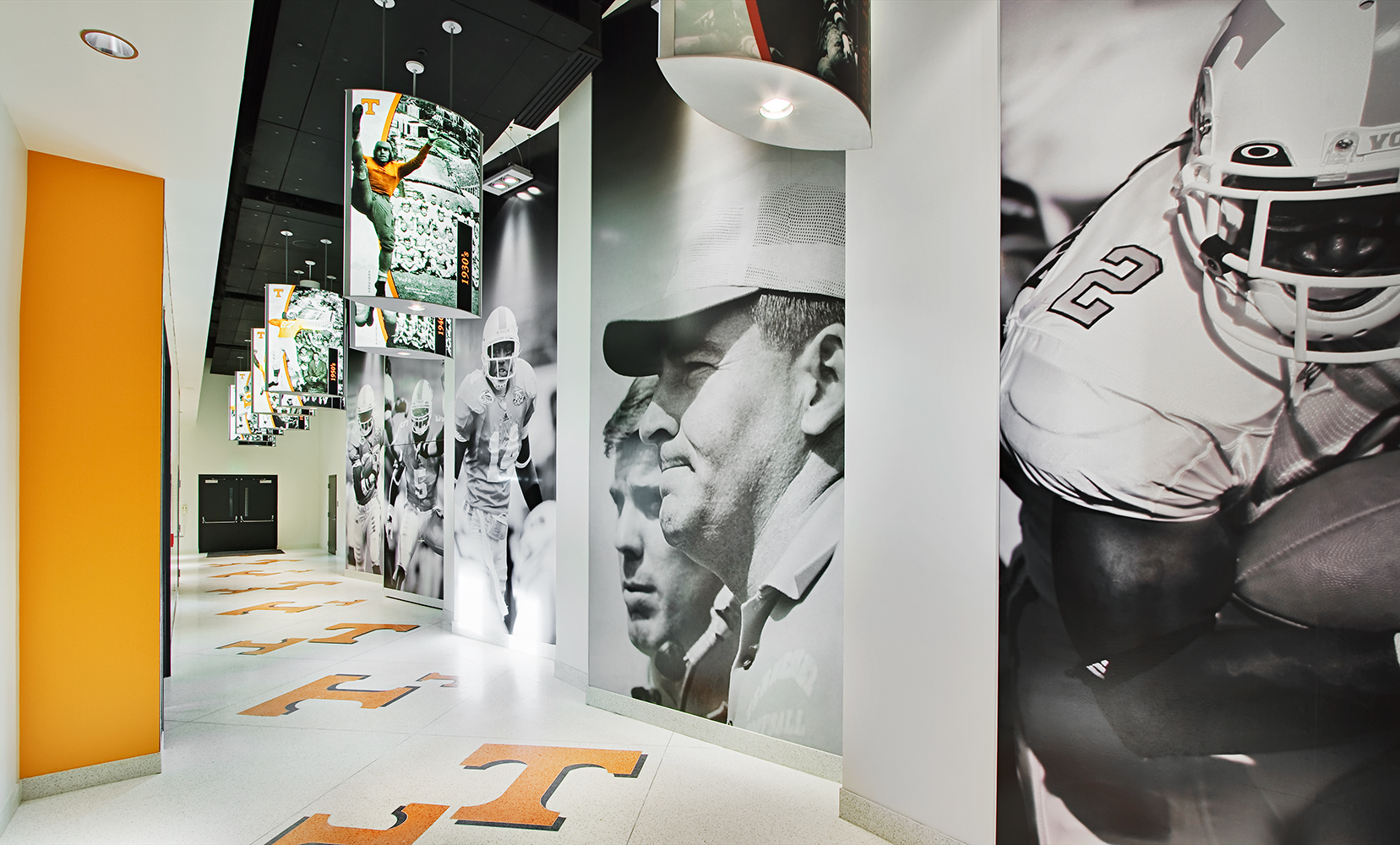 Air Foil custom light fixtures with photograph panels depicting college football players along a stadium hallway.
