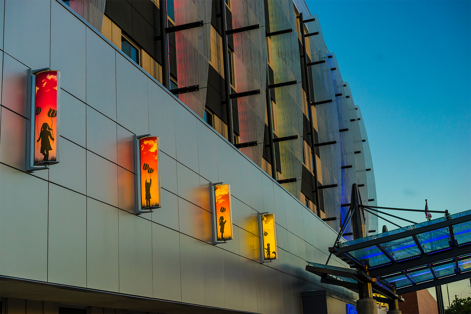 Air Foil custom light fixtures shine light through graphic designs to illustrate children playing with balloons.