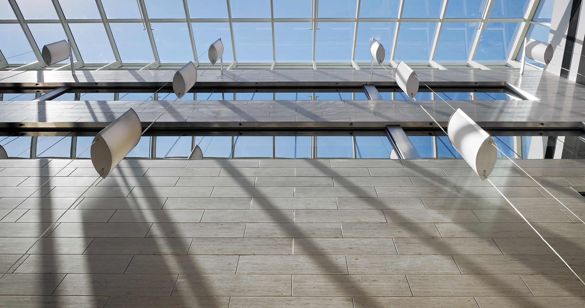 Air Foil custom light fixtures hung evenly, three to each string, and supported by cables along the fixture edges.