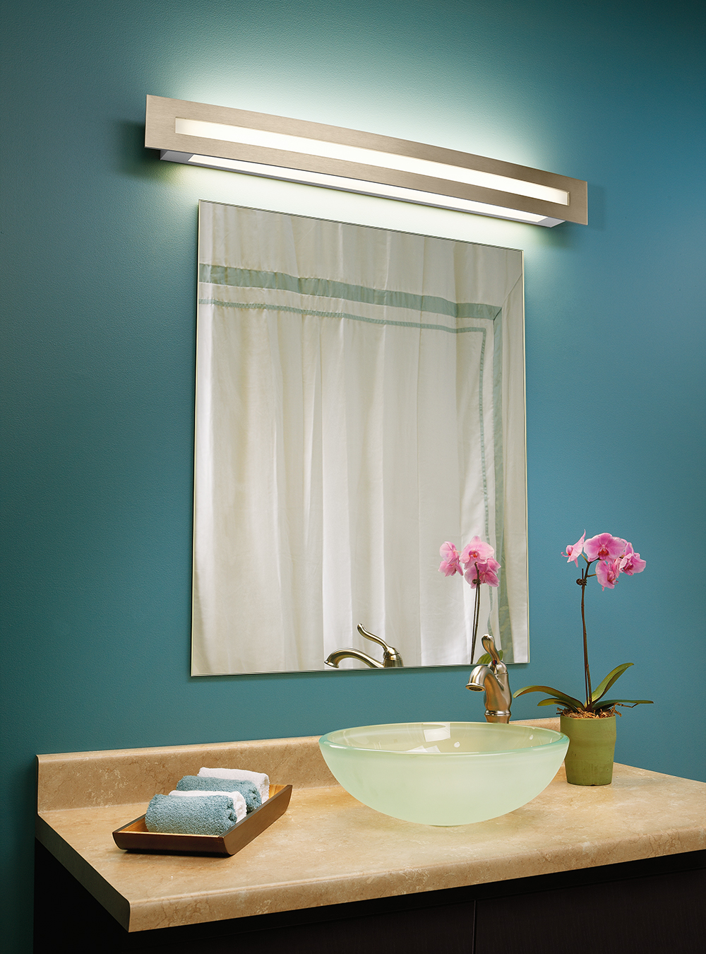 Blush modern vanity light above a simple bathroom mirror and a green wall
