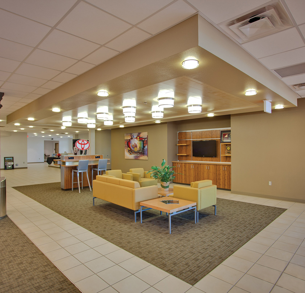 Capitol ceiling-mounted commercial lighting fixtures above a car dealership waiting area.