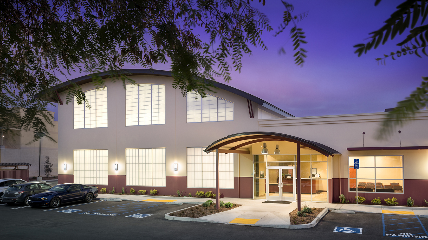 Colonnade outdoor light fixtures on the exterior wall of a modern healthcare facility at night.