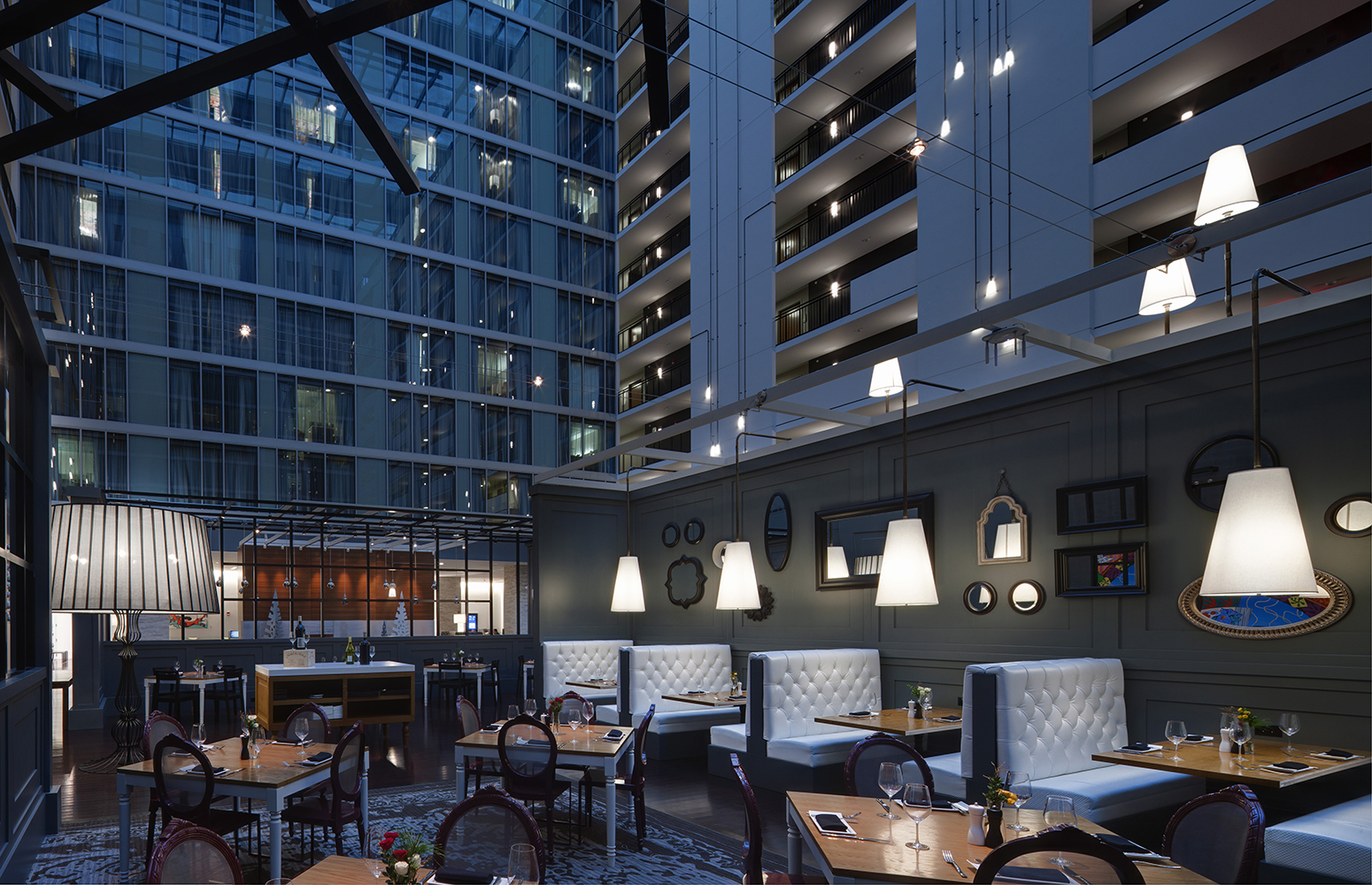 Unique, A-shaped custom light fixtures with square-angled black connecting pipes in an open hotel dining area.