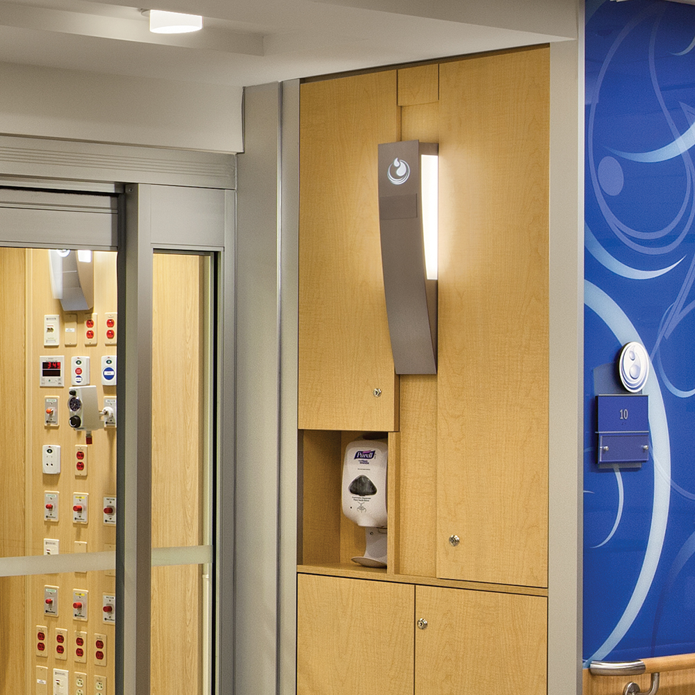 A cypress sconce on an exam room wall provides custom light fixtures with branded laser cut-outs.