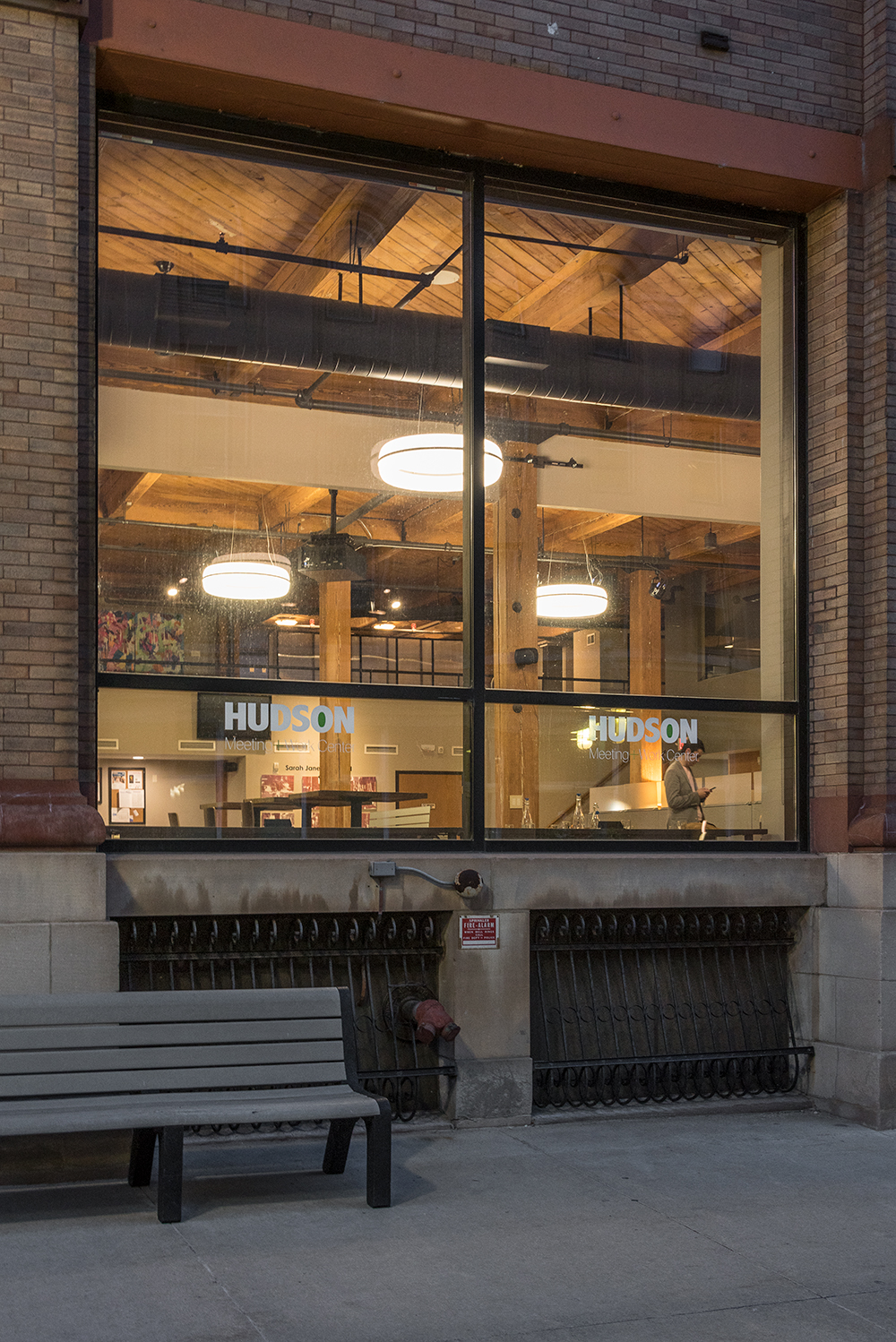 Meridian Round pendant is perfect for office lighting, viewed here from outside the window of an office building meeting center.