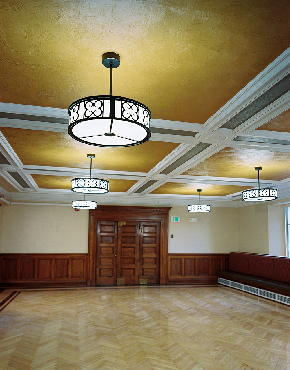Midland Arts custom light fixtures hung from a classically designed, detailed ceiling, overlooking a polished wood floor.