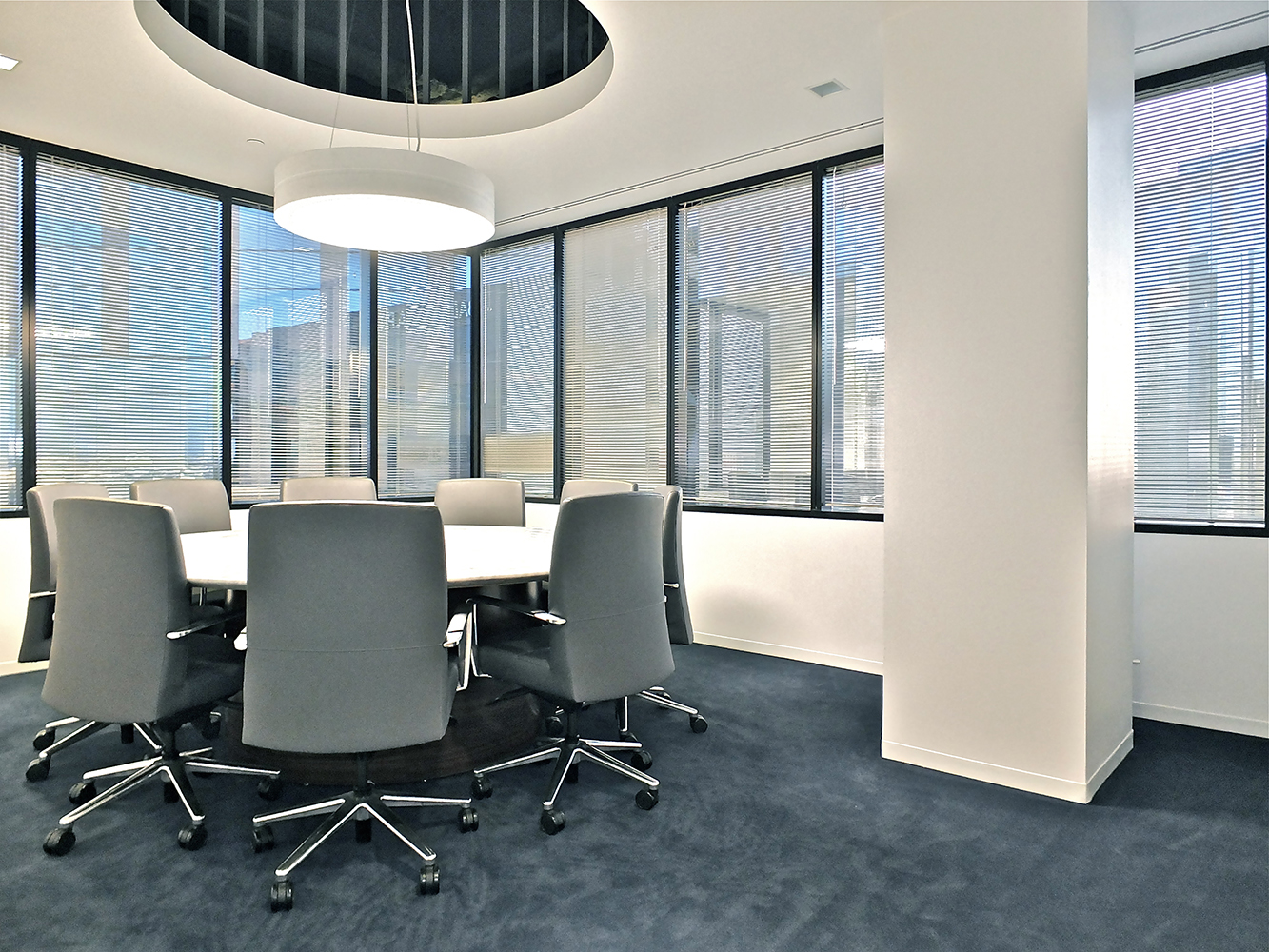 Omnience office lighting fixtures are perfect for conference tables, seen here above a small round table near large windows.