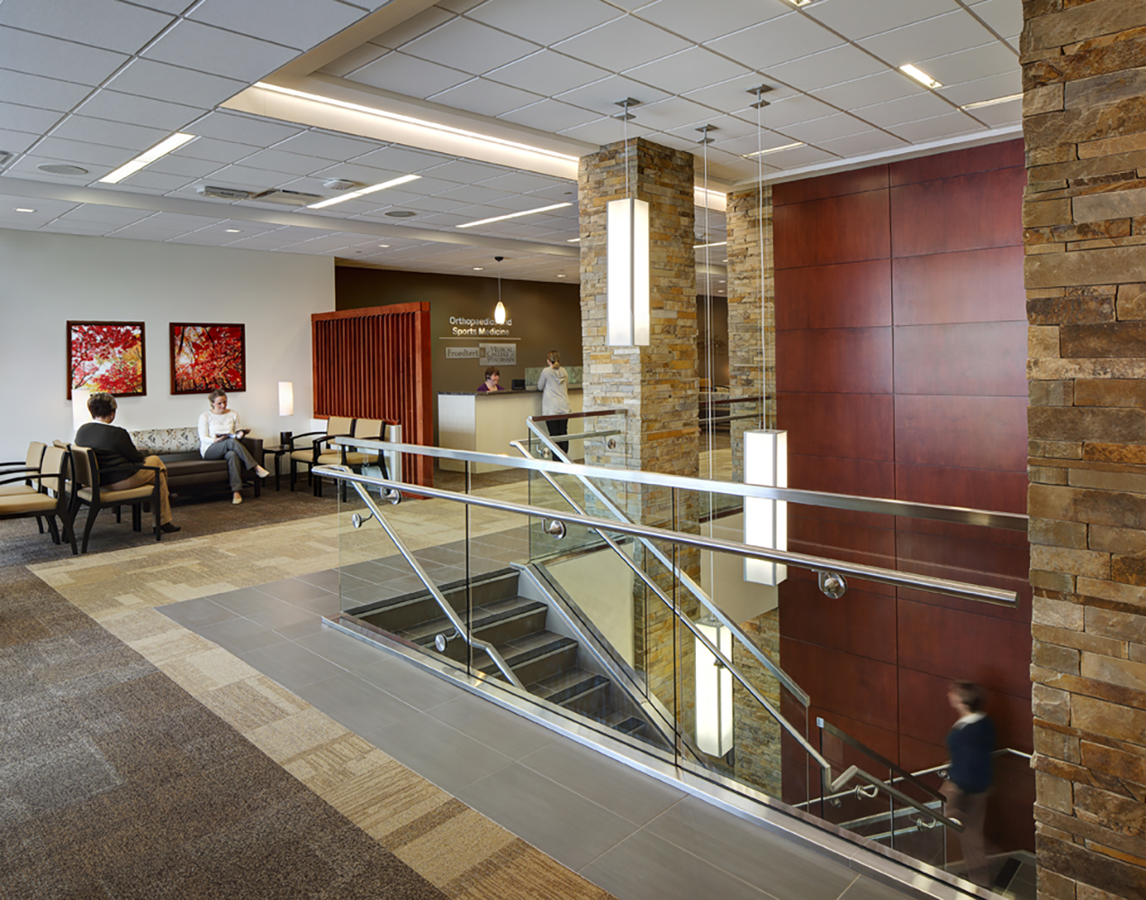 Parallel pendants in a hospital lighting application above a modern open stairwell near a cozy waiting area.