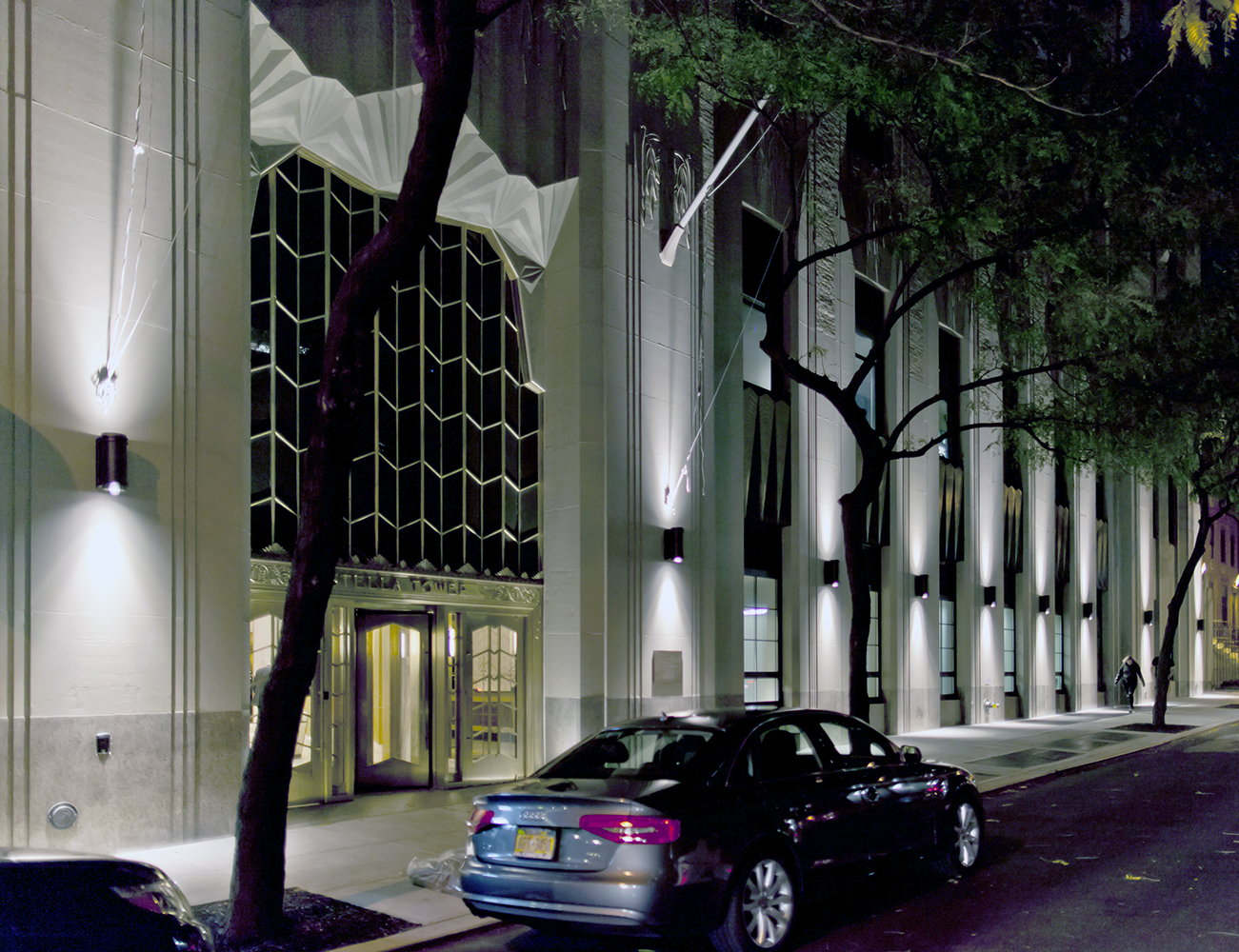 Pla outdoor light fixtures provide uplight and downlight on a commercial building exterior at night.