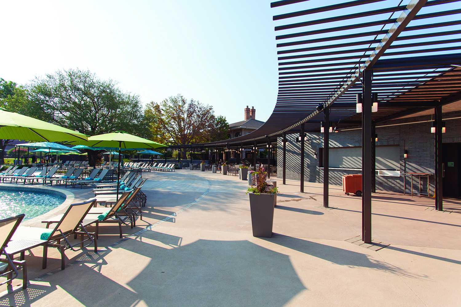 Scope modern lighting fixtures illuminate a poolside pergola structure.