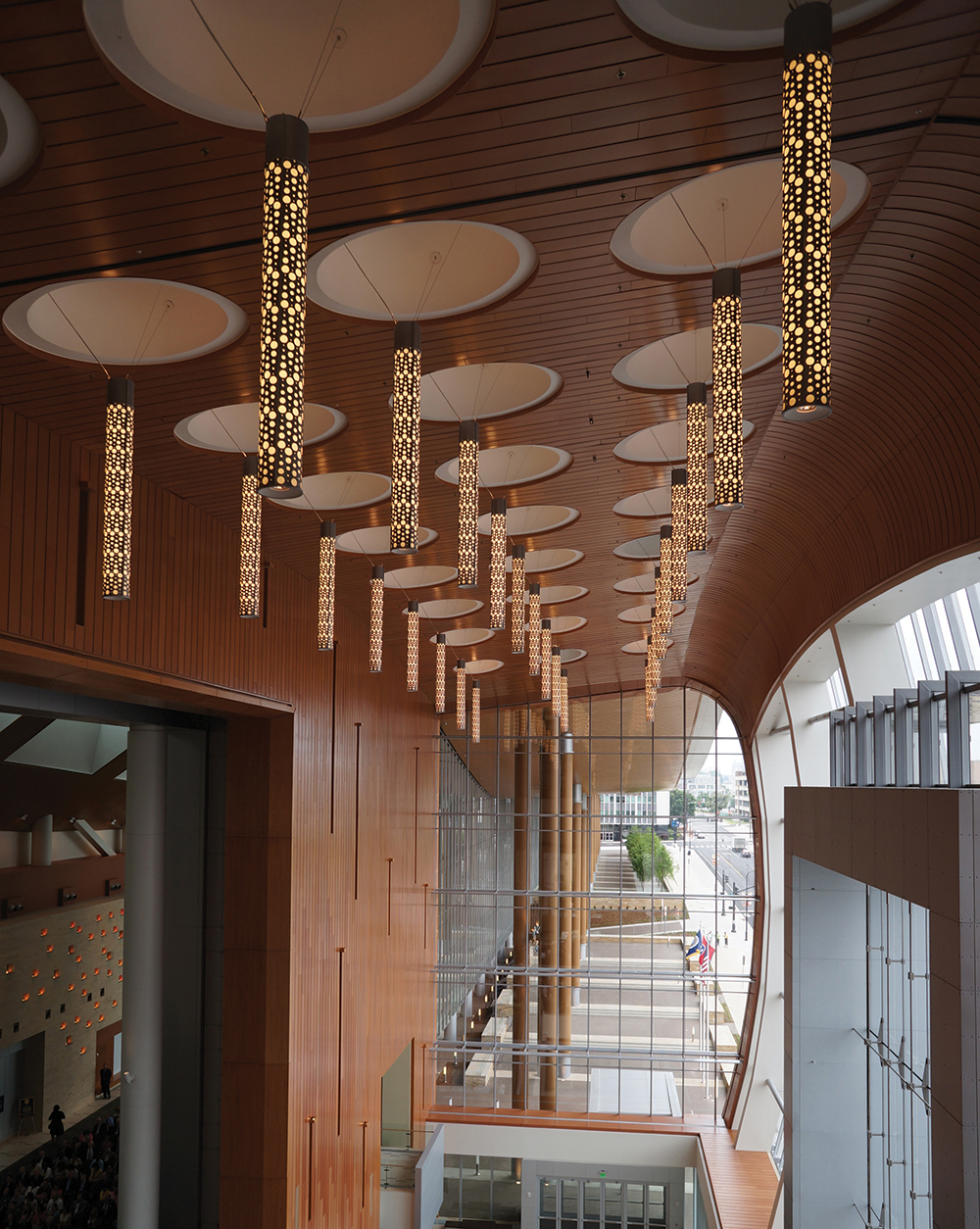 Sequence custom light fixtures with lace-like body design, mounted above a large, windowed entryway.
