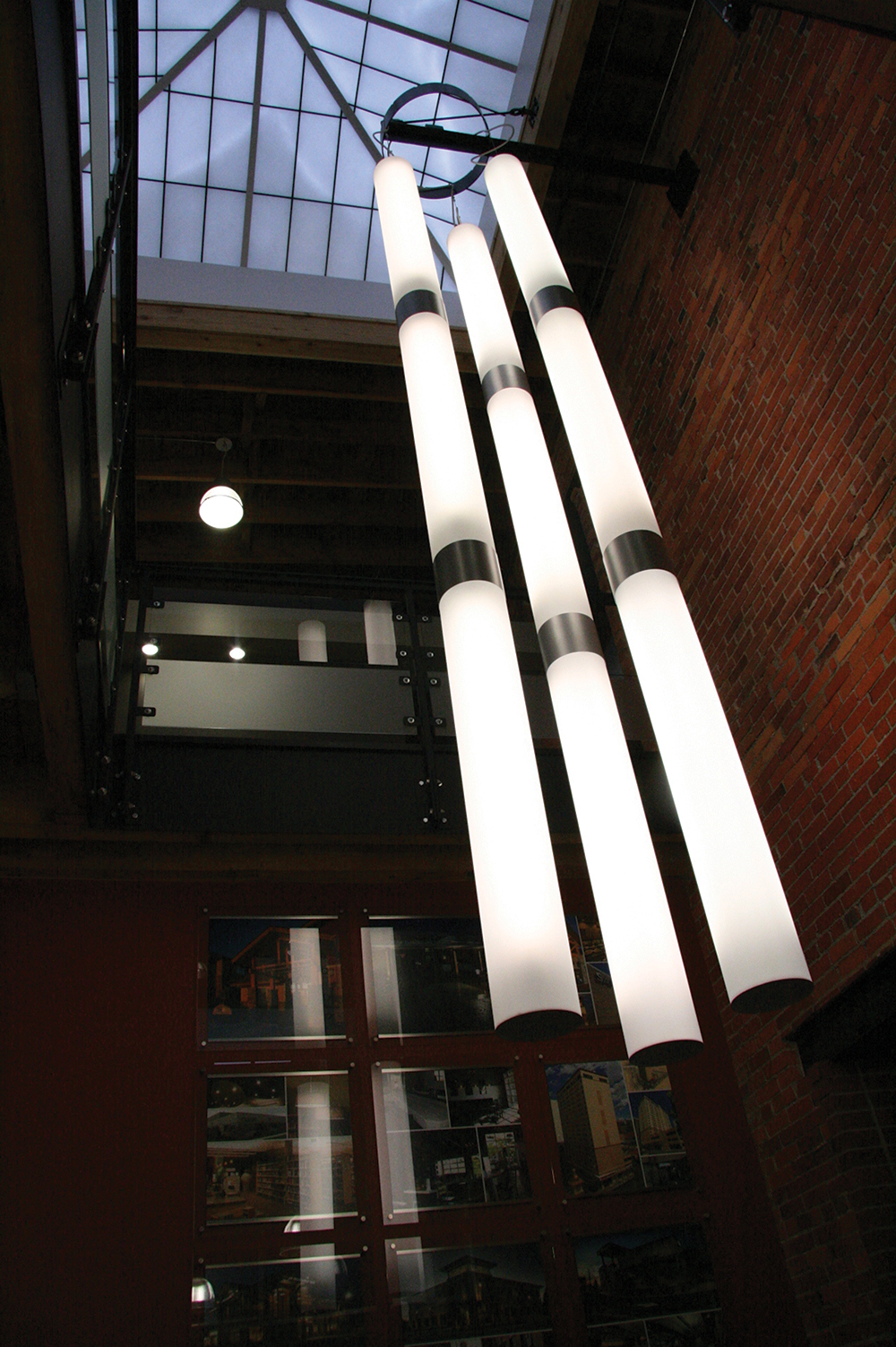 Sequence pendants linked in three tandem strands of three in a configuration of custom light-fixtures for an office lobby.