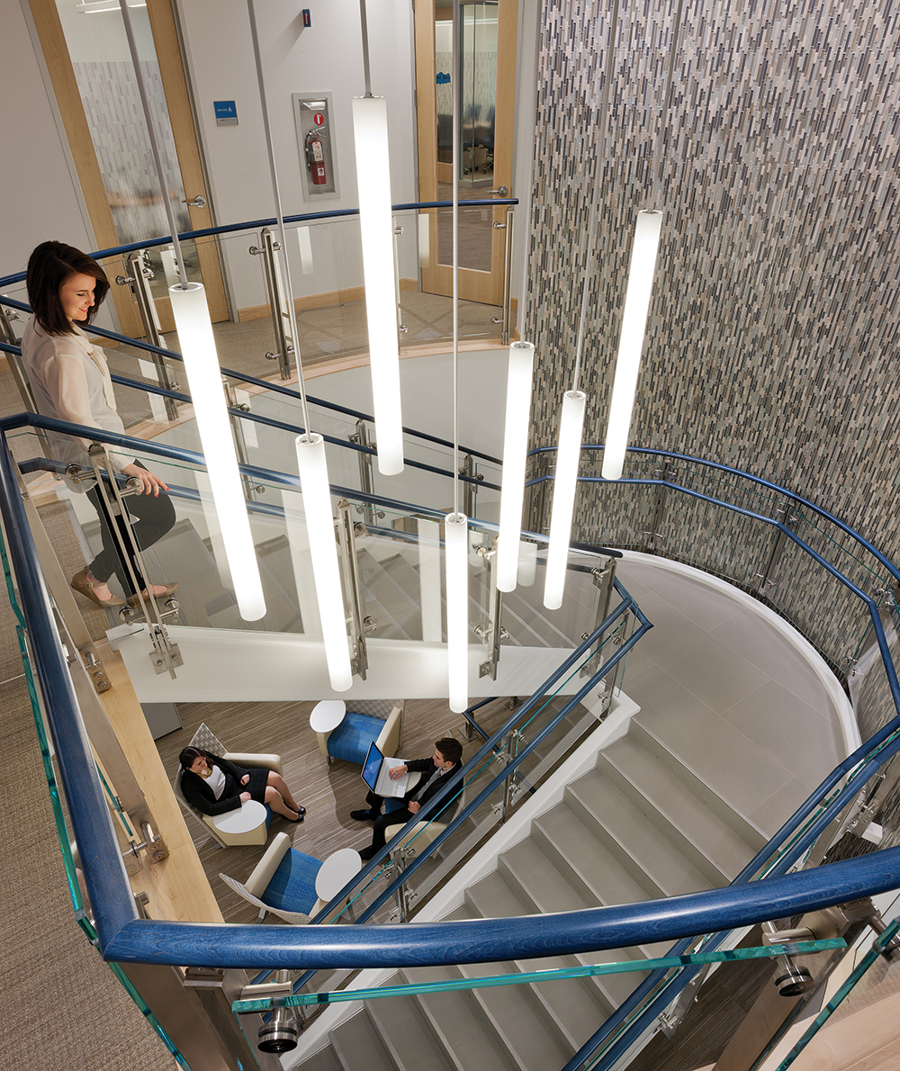 Sequence office lighting fixtures illuminate a modern staircase in a sleek multi-level office building.