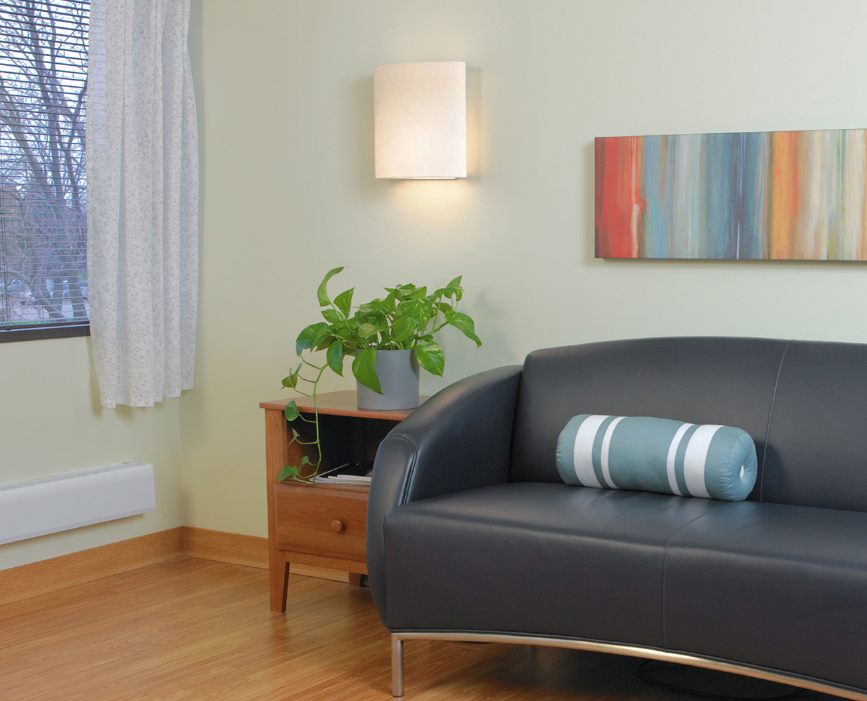 Unity wall sconce provides warm, inviting light in a hospitality lighting design near a sofa and side table.