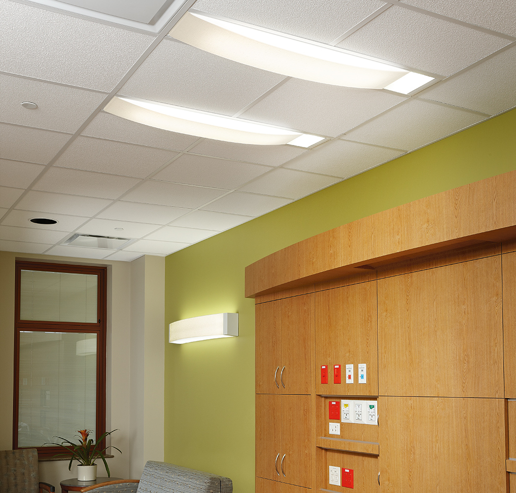 Unity medical lighting provides ceiling and wall lighting with pleasing, comforting shapes above a patient room seating area.