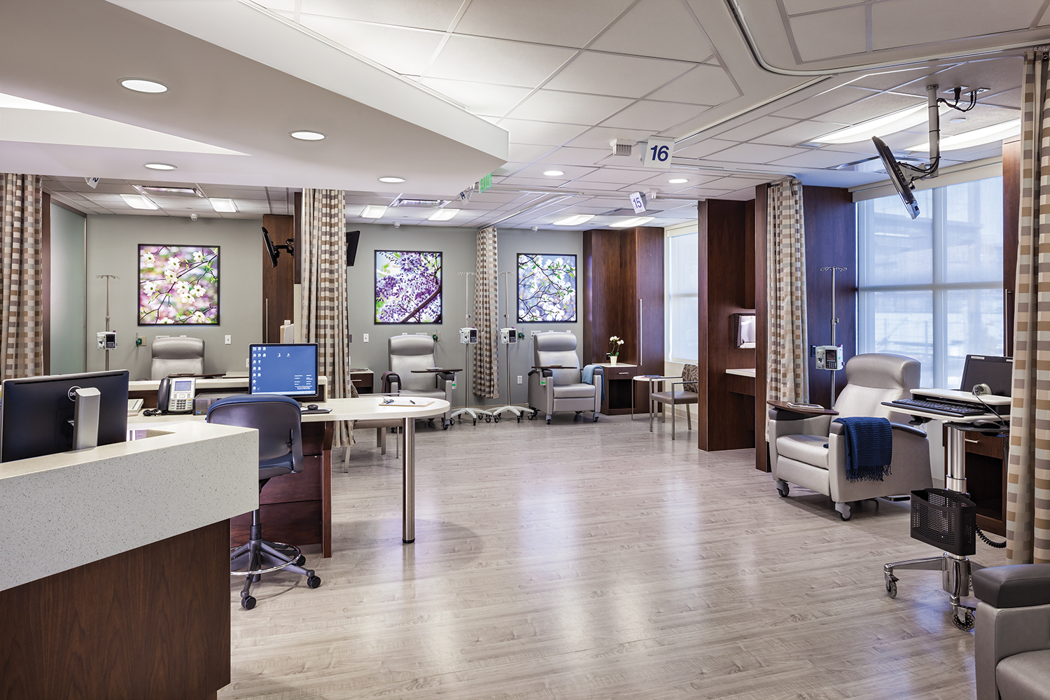 Unity medical lighting illuminates an infusion center with multiple patient seats and a nurse's station.