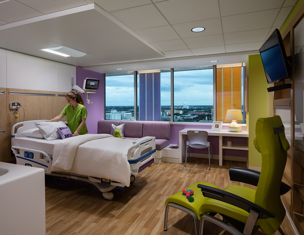 Unity overbed luminaire provides patient room lighting while a nurse adjusts the bedding.