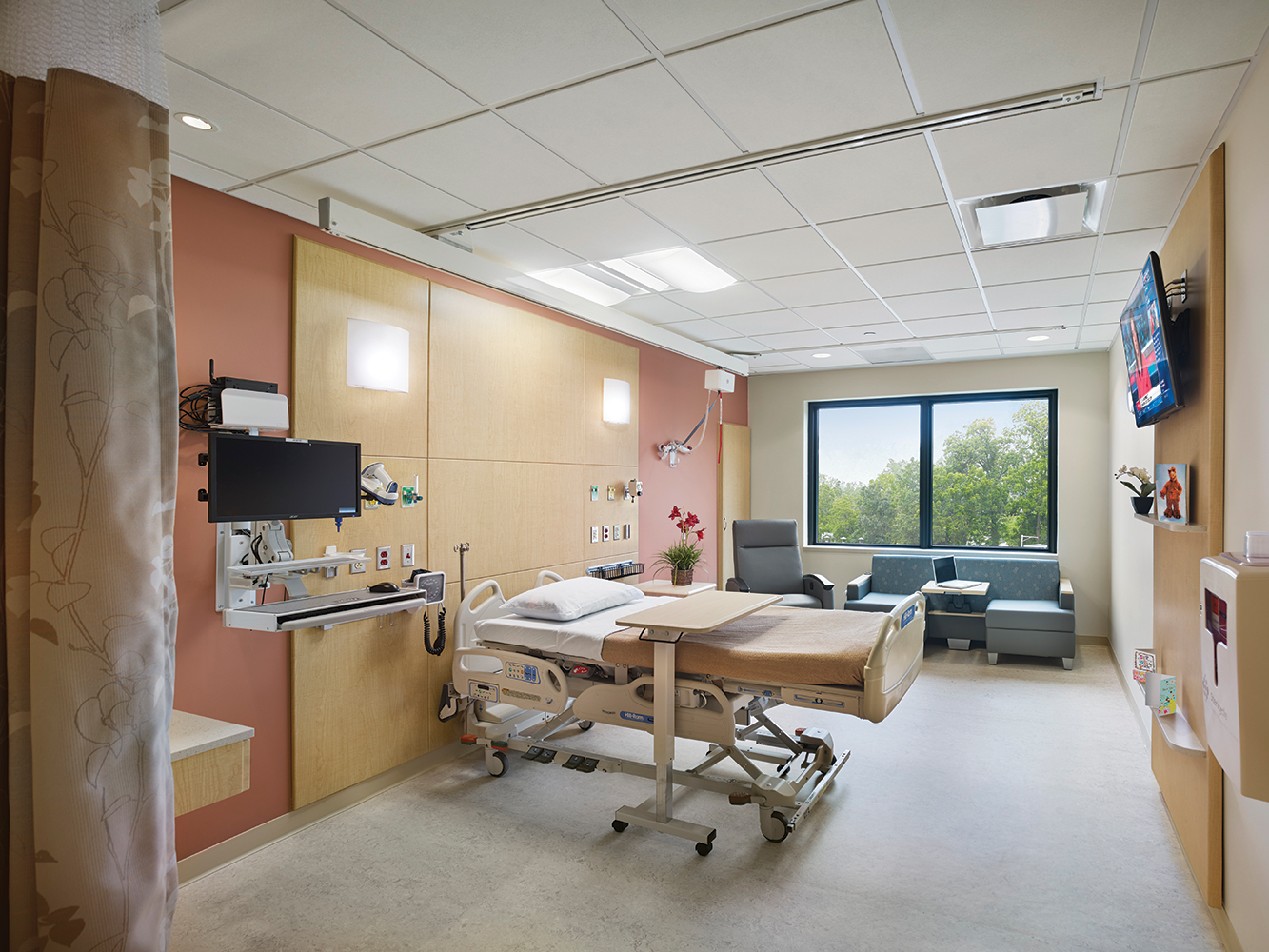 Unity overbed and wall sconce luminaires provide comforting medical lighting in a bright patient room.