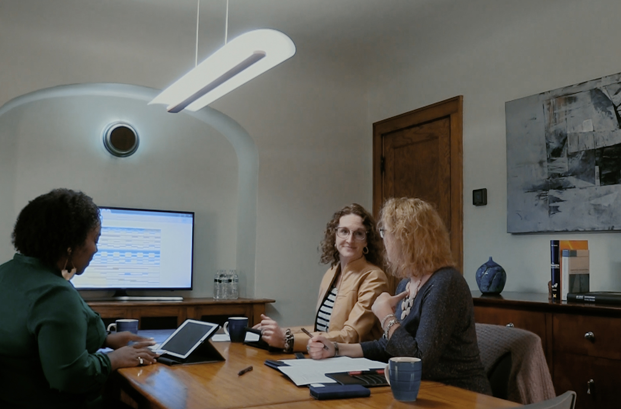 Conference room table with linear pendant light Volare hung over shared workspace